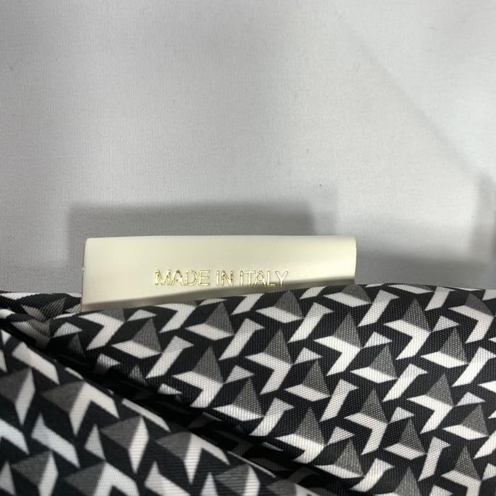 Țesătura geometrică alb-negru a lui ROBERTA PIERI, cu o etichetă albă pe care scrie "MADE IN ITALY" cu litere aurii. Fundalul este alb simplu.